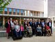 Die Beauftragten für Menschen mit Behinderungen von Bund und Ländern auf Sandboden vor einem hellen Backsteingebäude mit Balkon